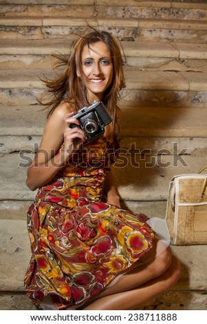 Lifestyle outdoor retro vintage young girl with a photographic camera in the city.