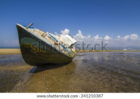 View of an old abandoned boat stranded on dry sand at the beach.