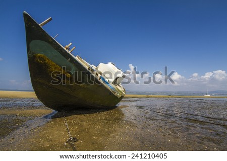 View of an old abandoned boat stranded on dry sand at the beach.