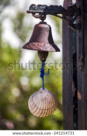 Close up view of a small rusty bell with a shell serving as a door bell.