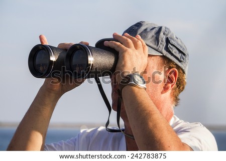 View of a man with binoculars watching the sea horizon.