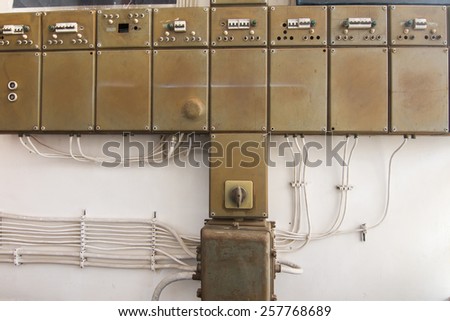 View of old row of electrical boxes on a wall.
