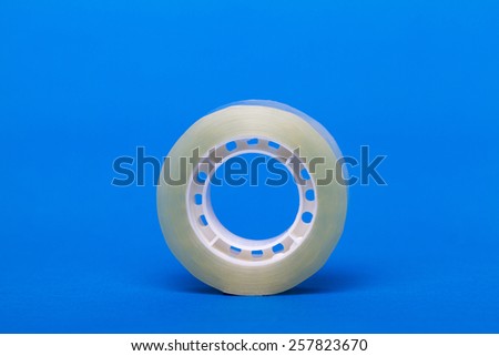 Roll of transparent sticky tape over a blue background.