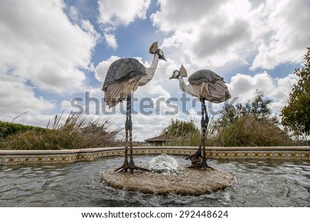 View of two stone statues of crane birds in a water fountain.