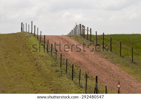 View of a hill with a fence and dirt road in Alentejo, Portugal.