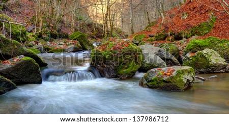 Autumn river cascade with sunlight in background