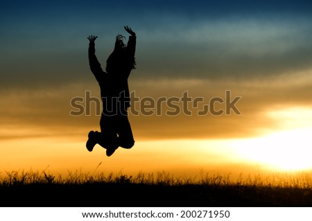 Silhouette of girl jumping in sunset.