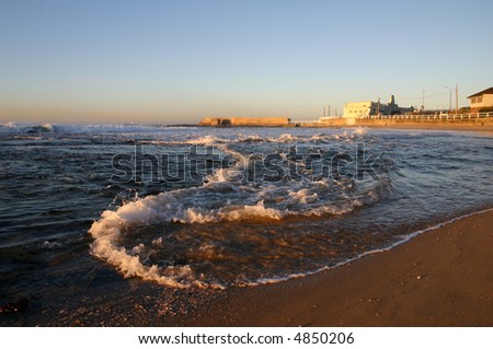 A wave rolls along the shore as the tide comes in on a stretch of sand at Newcastle Australia.