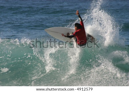 A surfer turns off the top of a wave sending spray flying.