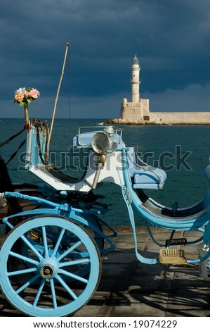 Blue traditional carriage with flowers and lighthouse on the background