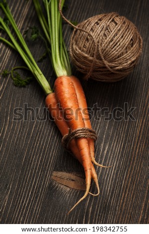Still life with raw carrots on dark wooden table and twine