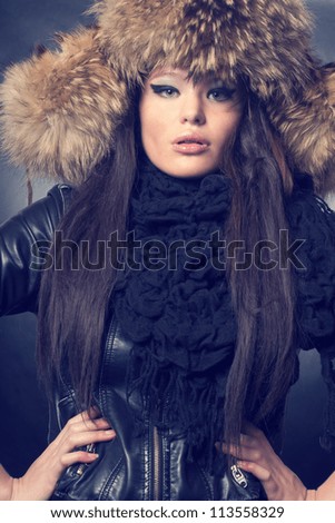 Fashionable woman in a fur hat and a leather jacket. Winter style.