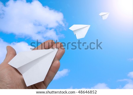 The hand starting paper planes in the sky.