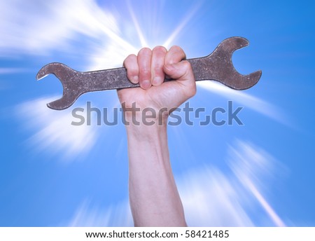 Hand with a wrench on a background of the sparkling sky.