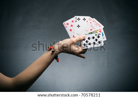 woman's hand holding playing cards on dark background