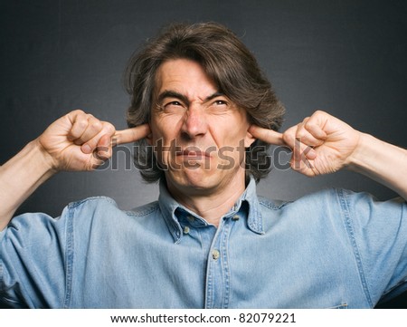A man covers his ears with his hands. Suffering from a loud sound.