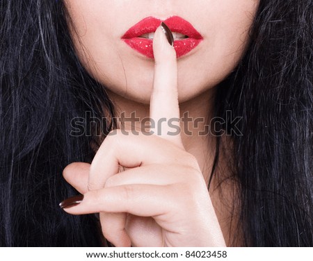 Foto de Portrait of flirty girl showing shhh taboo sign with finger on lips  do Stock