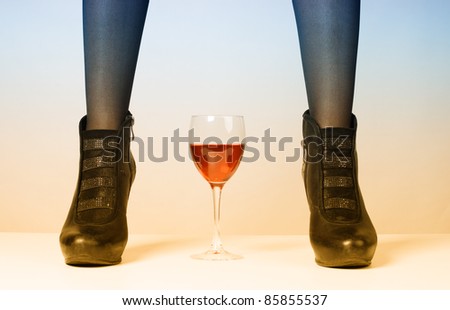 Female legs in shoes on a high heel and a glass of red wine.