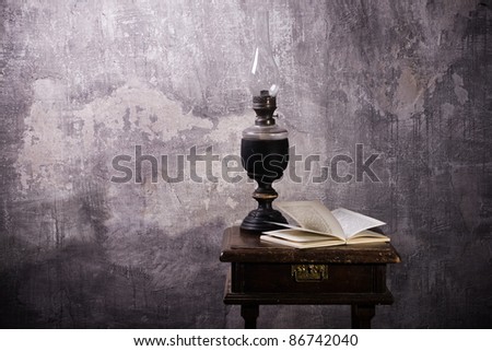 The old kerosene lamp and open book against a stone wall.