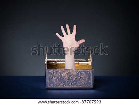 A human hand protruding from the open chest with money.