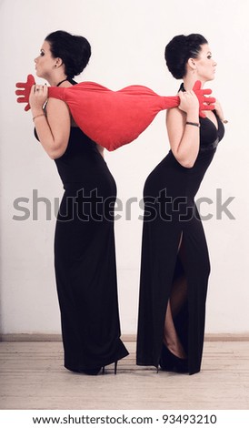 Two women in long dresses pulled the pillow in the shape of the heart in different directions. The conflict.