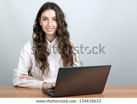 Young smiling woman with laptop sitting at the table.