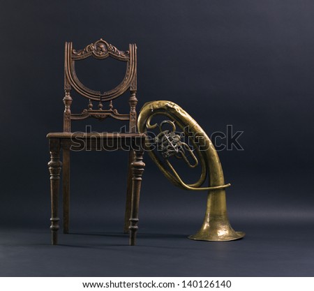 Vintage wooden chair and trumpet on a black background.