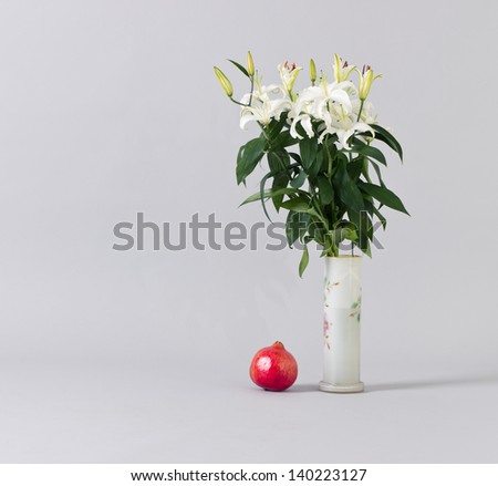 White lilies in a vase and red garnet.  still life in the interior.