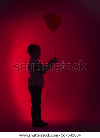 Little boy giver balloon in the shape of a heart.