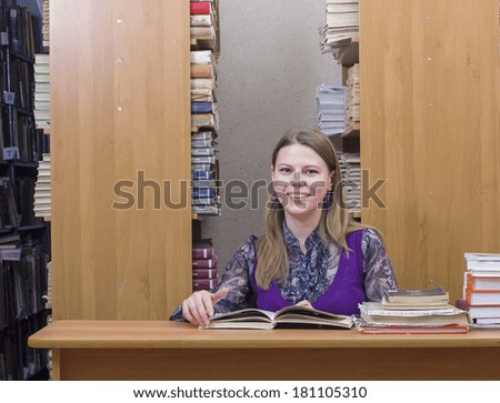 Portrait of clever student with open book reading it in college library