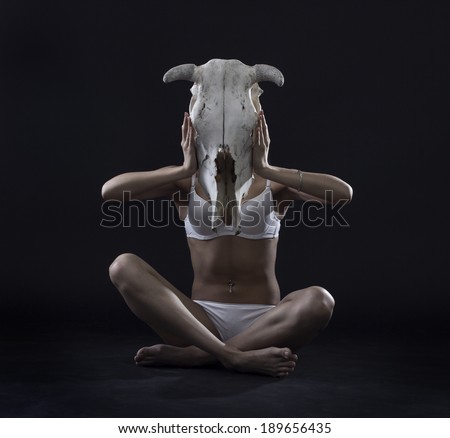 Perfect female body with cow skull in his hands.