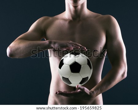Soccer player with a soccer ball in his hands on a dark background.