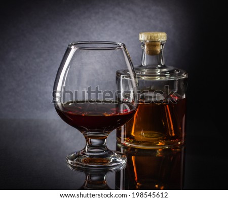 Cognac bottle and glass on the dark background.