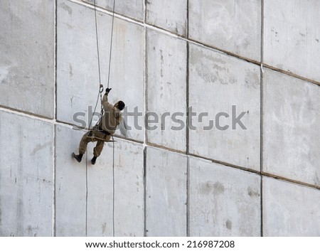 Construction worker performs painting hanging on the wall of the house.