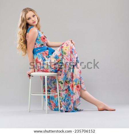 Beautiful young woman sitting in a trendy long dress