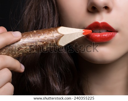 Woman paints her lips with a red pencil. Red lips close-up.