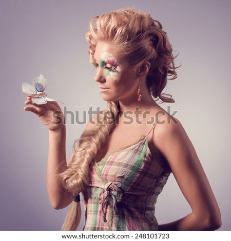 Beautiful girl takes a butterfly in her hand. Summer fairy portrait. Long permed hair.