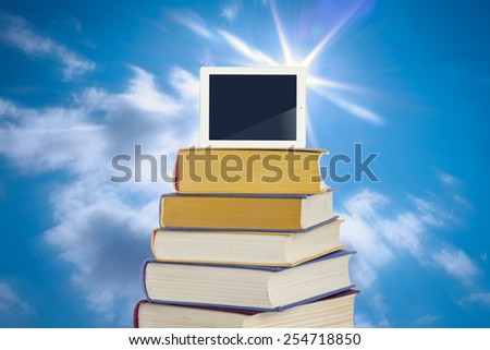 Digital tablet on top of the pile of books.
