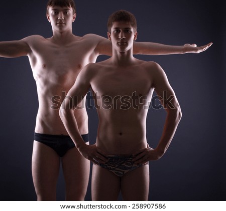 Man torso isolated on a black background. Two muscular men posing on a dark background.