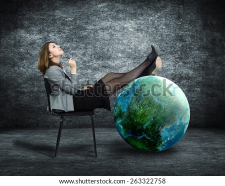 Young business woman dreaming sitting on a chair and put his feet on the globe.