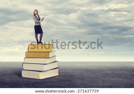 Successful young woman standing on top of the foot pointing to the books free space for your Publicity.