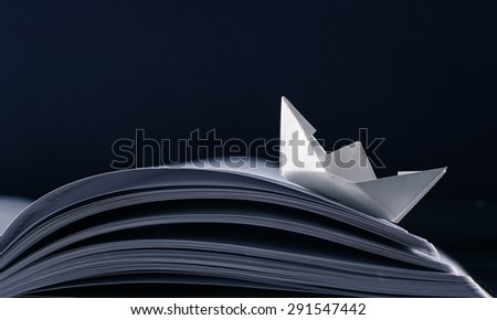 Paper boat floating on the pages of a notebook.
