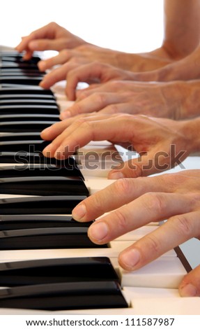 Six hands playing simultaneously on a grand piano with bright white background
