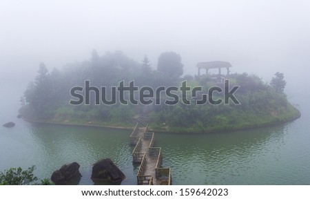 island with bridge on the lake in fog