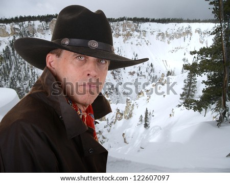 Handsome cowboy wearing a red scarf against a snowy winter canyon