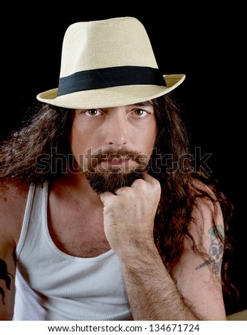 very handsome sexy man with long wavy brown hair and striking eyes wearing a straw fedora with a black band