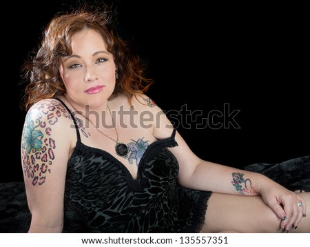 Beautiful woman with auburn hair and striking gold eyes wearing black leopard print with tattoos