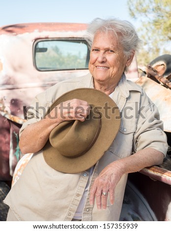 Smiling lady with a hat leaning against a vintage truck