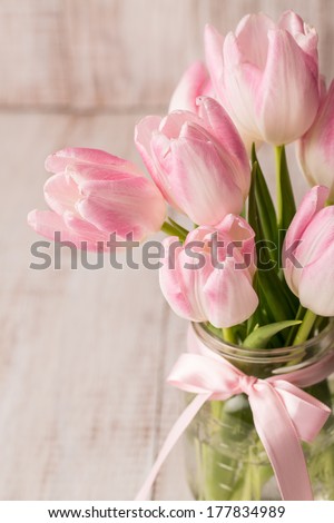Pink and white Tulips in glass jar vase with pink bow