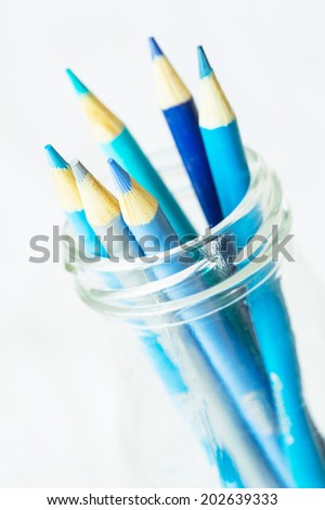 Pastel cool blue color pencils in glass jar on white